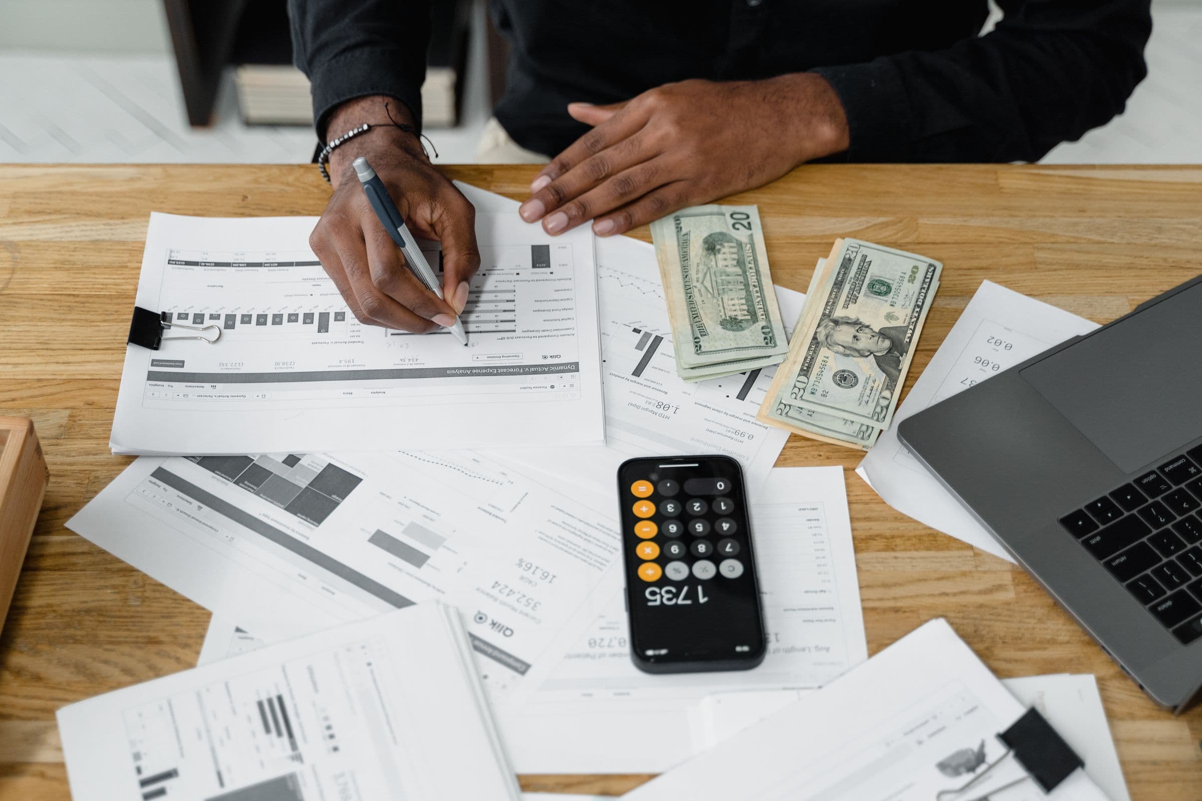Mesa de trabalho contábil com relatórios financeiros, calculadora e notebook